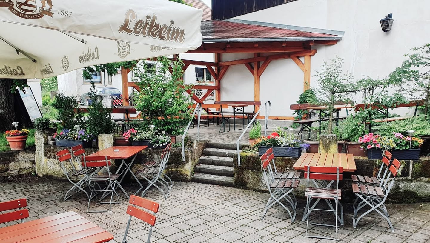 Biergartenterrasse mit roten Klapptischen und Treppe